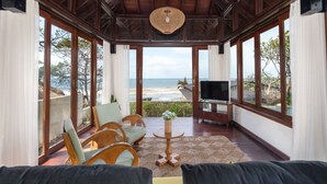 Een ruim balkon met uitzicht op het strand, houten meubels en een televisie.