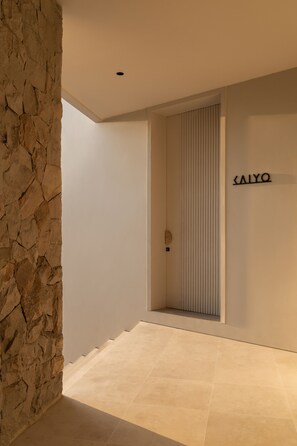 A modern interior with a stone wall, a minimalist door, and a sign reading "SALYO".