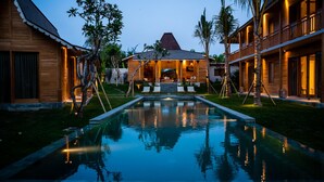 A resort with a swimming pool, wooden buildings, and a well-maintained garden.