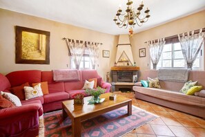 A living room with a fireplace, two sofas, a coffee table, and a chandelier.