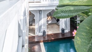 A pool area with a wooden deck, white lattice structures, and a dog sitting on a bench. - Beautiful 6BR Villa W/Pool & Spa room, Bali villa 2238 (Bali)