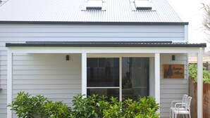 A single-story house with a covered porch, a sliding glass door, and a small wooden sign that reads "Ocean Alley".