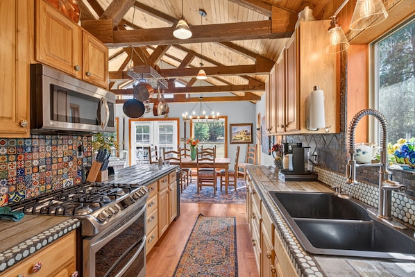 A kitchen with wooden cabinets, a gas stove, a microwave, and a large window.