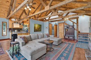 A spacious living area with a large sectional sofa, a small coffee table, and a patterned rug.