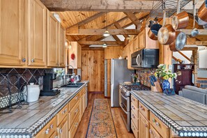 A kitchen with wooden cabinets, a tiled backsplash, and a central island with a sink.