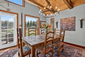 A dining area with a wooden table and chairs, a chandelier, and a painting on the wall.