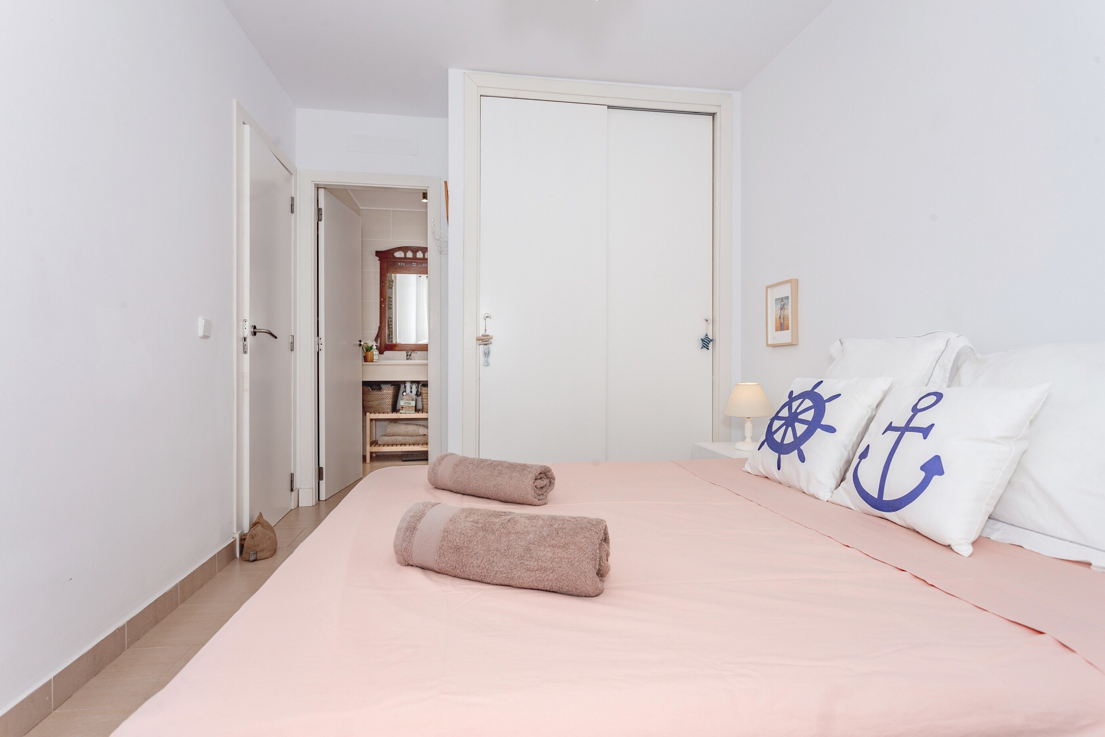 Un dormitorio con cama, almohadas, una puerta y un pasillo.