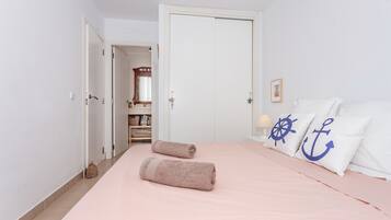 Un dormitorio con cama, almohadas, una puerta y un pasillo.