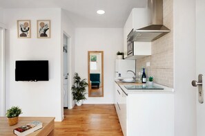 A modern kitchen with white cabinets, a stainless steel range hood, and a small island with a sink.