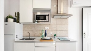 Une cuisine moderne équipée d’un four à micro-ondes encastré, d’une hotte en acier inoxydable et d’un réfrigérateur blanc.