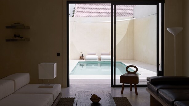 A modern living room with a large sliding glass door leading to a pool area. - Tekko Villa Umalas (Kerobokan)