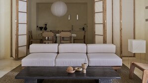 A modern living room with a sectional sofa, a dark wooden coffee table, and a dining area in the background. - Tekko Villa Umalas (Kerobokan)