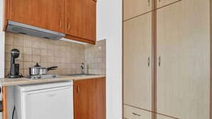 A kitchen with wooden cabinets, a white refrigerator, a stove, and a sink. - Studio Apartment 'Panorama 2' with Sea View, Wi-Fi and Air Conditioning (Lefkada)