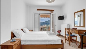 A bedroom with a bed, wooden dresser, desk, chair, and a TV. - Studio Apartment 'Panorama 2' with Sea View, Wi-Fi and Air Conditioning (Lefkada)