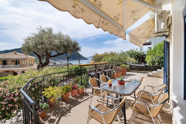 A terrace with outdoor seating, potted plants, and a view of the sea.