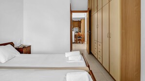 A hotel room with two beds, wooden wardrobe, and a view into the dining area. - Apartment 'Panorama 2' with Sea View, Wi-Fi and Air Conditioning (Lefkada)