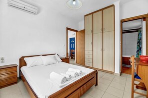 A bedroom with a wooden bed, a wardrobe, a desk, and a bathroom visible through an open door. - Apartment 'Panorama 2' with Sea View, Wi-Fi and Air Conditioning (Lefkada)