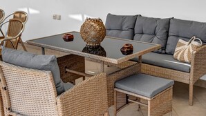 A wicker sofa with grey cushions, a wicker table with a glass top, and a woven vase. - Apartment 'Panorama 2' with Sea View, Wi-Fi and Air Conditioning (Lefkada)