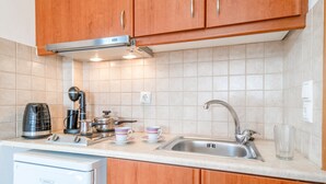 A kitchenette with a coffee maker, kettle, and cups on the counter, a sink, and a dishwasher. - Studio Apartment 'Panorama 1' with Sea View, Wi-Fi and Air Conditioning (Lefkada)