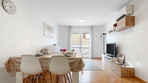 Una sala de estar moderna con comedor, televisión y balcón con vistas.
