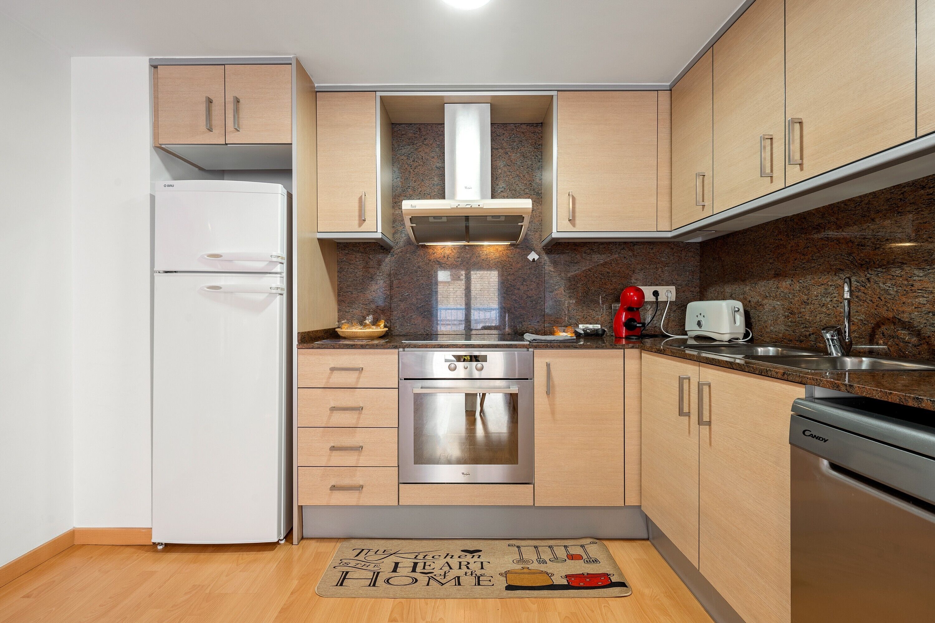 Una cocina moderna con electrodomésticos de acero inoxidable, armarios de madera y encimera de granito.