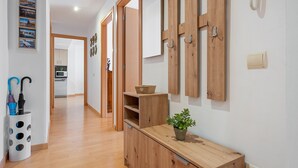 Un pasillo con puertas de madera, un armario de madera con una planta y un teléfono fijo en la pared.