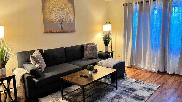 A modern living room with a sofa, coffee table, and a painting on the wall.