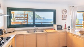 Une cuisine avec vue sur la mer, un grille-pain, un four à micro-ondes et un évier.