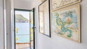 Un couloir donnant sur la mer, orné de cartes encadrées au mur, et une porte menant à l’extérieur.