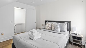 Une chambre à coucher moderne avec un grand lit, une table de chevet et une commode.