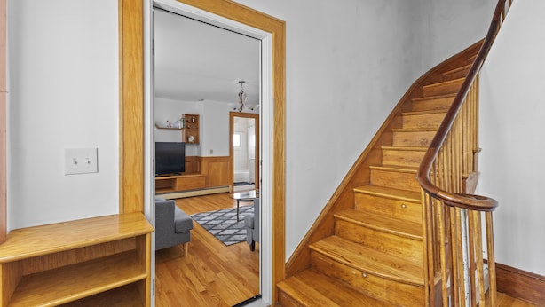 Un escalier en bois, doté d’une rampe, mène à une pièce où se trouvent un canapé et une petite table.
