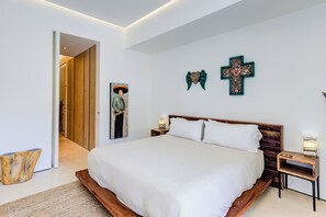 Camera da letto moderna con un letto grande, una testiera in legno e due decorazioni a croce appese al muro.