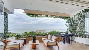 A modern outdoor seating area with wooden furniture and a view of the cityscape. - Designer SoHOPV w/th Ocean Views (Puerto Vallarta)