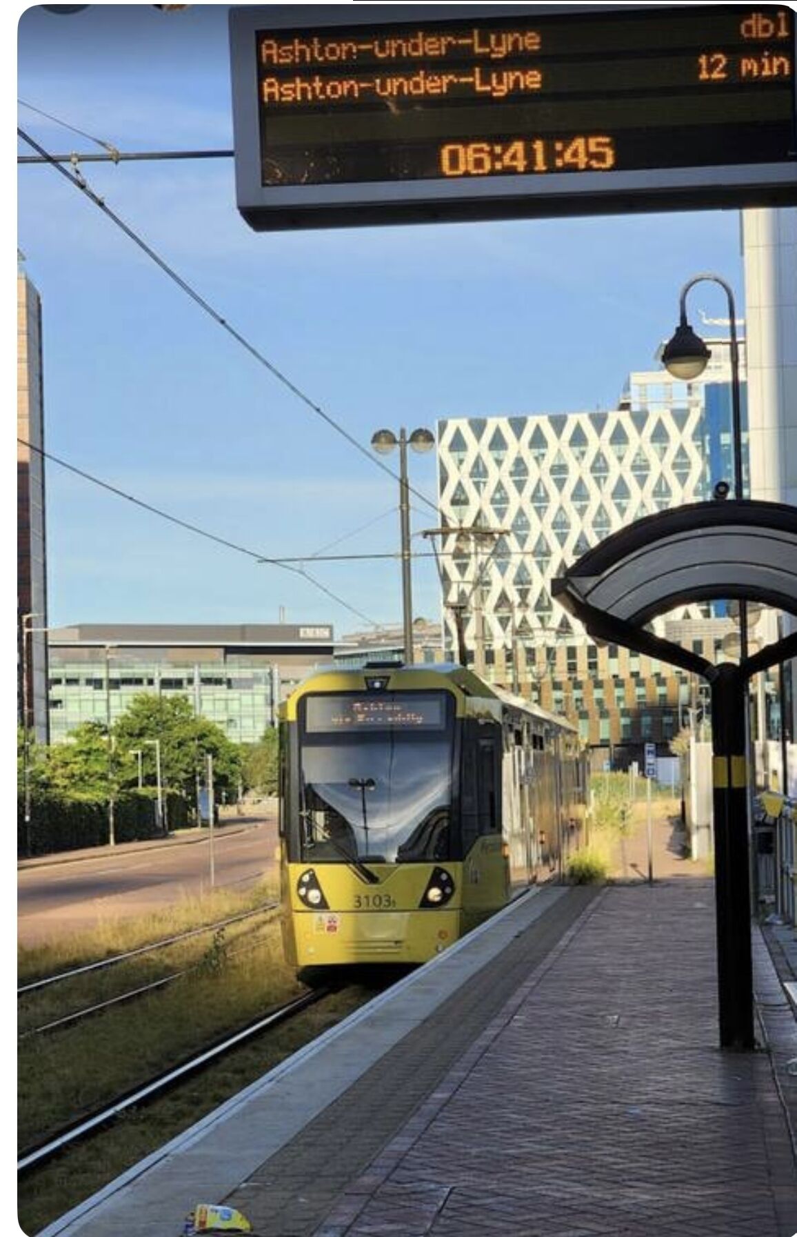 A tram station with a digital display indicating a 12-minute wait.