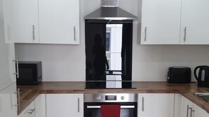 A modern kitchen with white cabinets, a stainless steel range hood, a microwave, and a toaster.