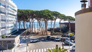 Hotel à beira-mar com estacionamento, vista para o oceano e uma fileira de palmeiras.