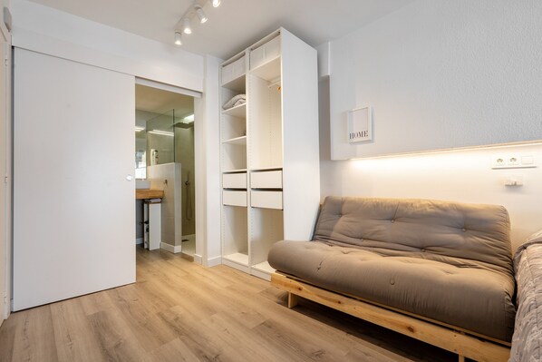 A modern room with a wooden floor, a beige sofa, a white wardrobe, and a 'HOME' sign on the wall.