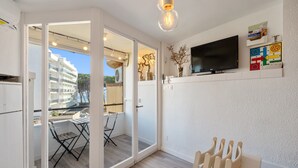 Sala de estar moderna com televisão, mesa de jantar e varanda com vista para um edifício.