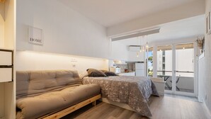 Um quarto moderno com sofá, cama, um letreiro 'HOME', varanda e área de cozinha.