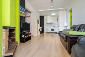 Una sala de estar con chimenea, televisor y sofá.