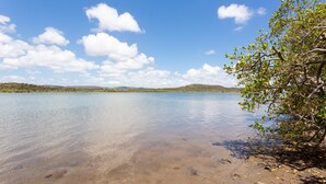 A clear lake with calm water, surrounded by hills and trees. - Causeway's Pinnacle! (Yeppoon)