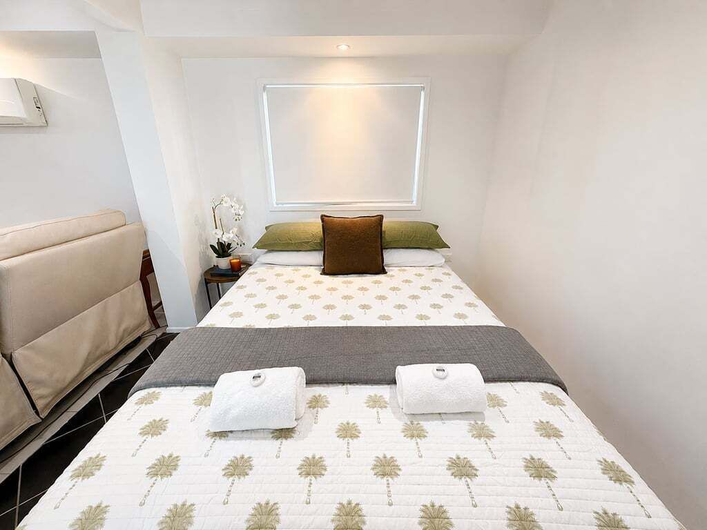 A hotel room with a bed, a nightstand, a lamp, and a window.