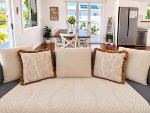 A modern living room with a sofa, a dining table, and a kitchen area. - Causeway's Pinnacle! (Yeppoon)