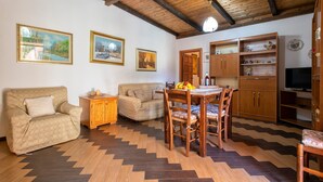 Un salon comprenant un canapé, une table à manger avec des chaises, des meubles en bois et un téléviseur.