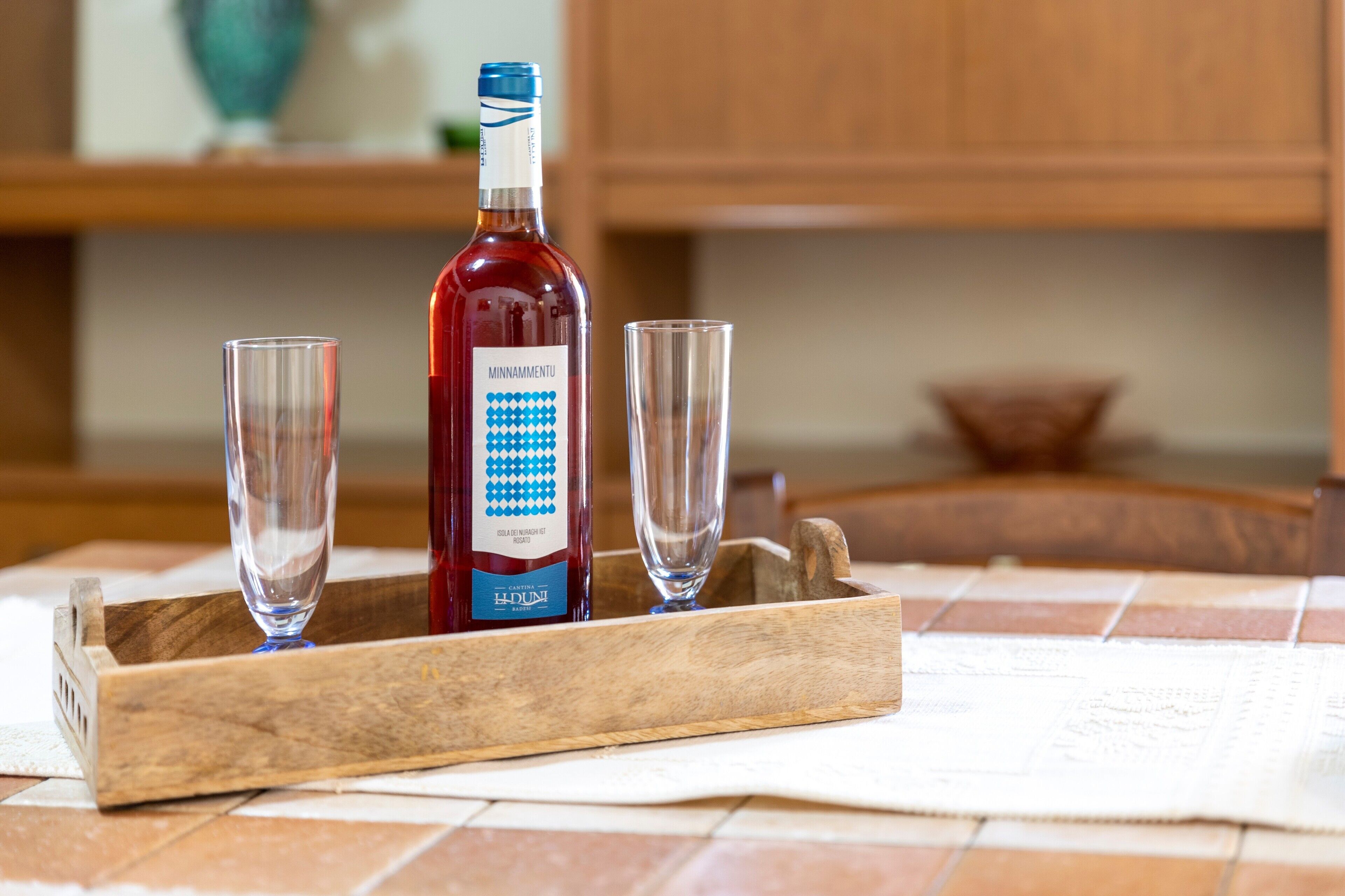 Eine Flasche Minammentu-Wein und zwei Gläser auf einer Holztischplatte.