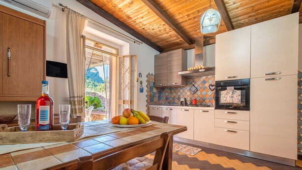 Une cuisine avec des meubles en bois, un pare-feu en carrelage et un coin repas avec une table mise pour deux personnes.