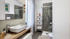 Un baño moderno con un lavamanos grande, una ducha y un inodoro.