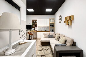 Ein kompakter Wohnbereich mit Küchenzeile, einer Couch, einem Couchtisch und einer Lampe.