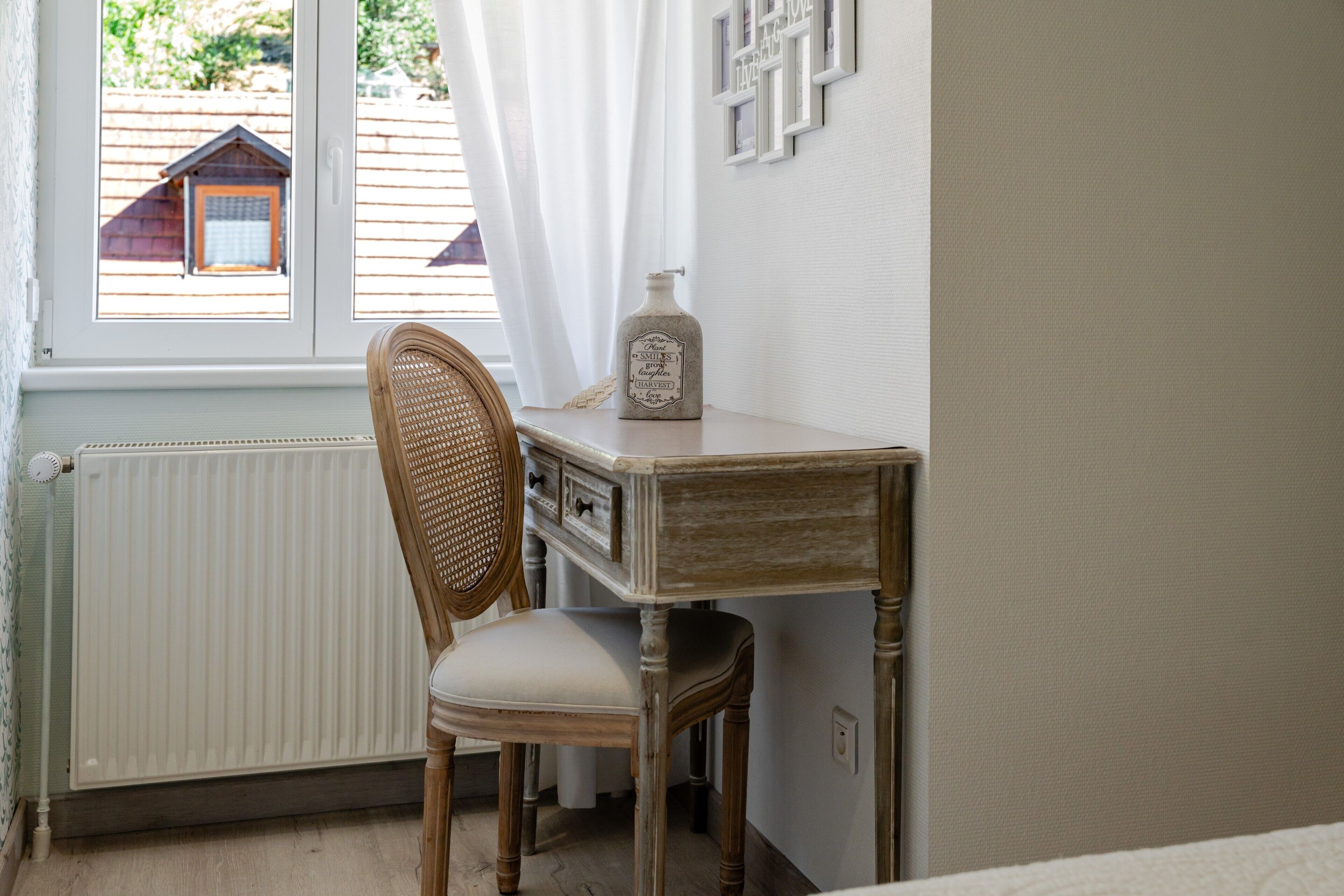 Een kamer met een houten stoel, een tafeltje, een radiator en een raam met gordijnen.