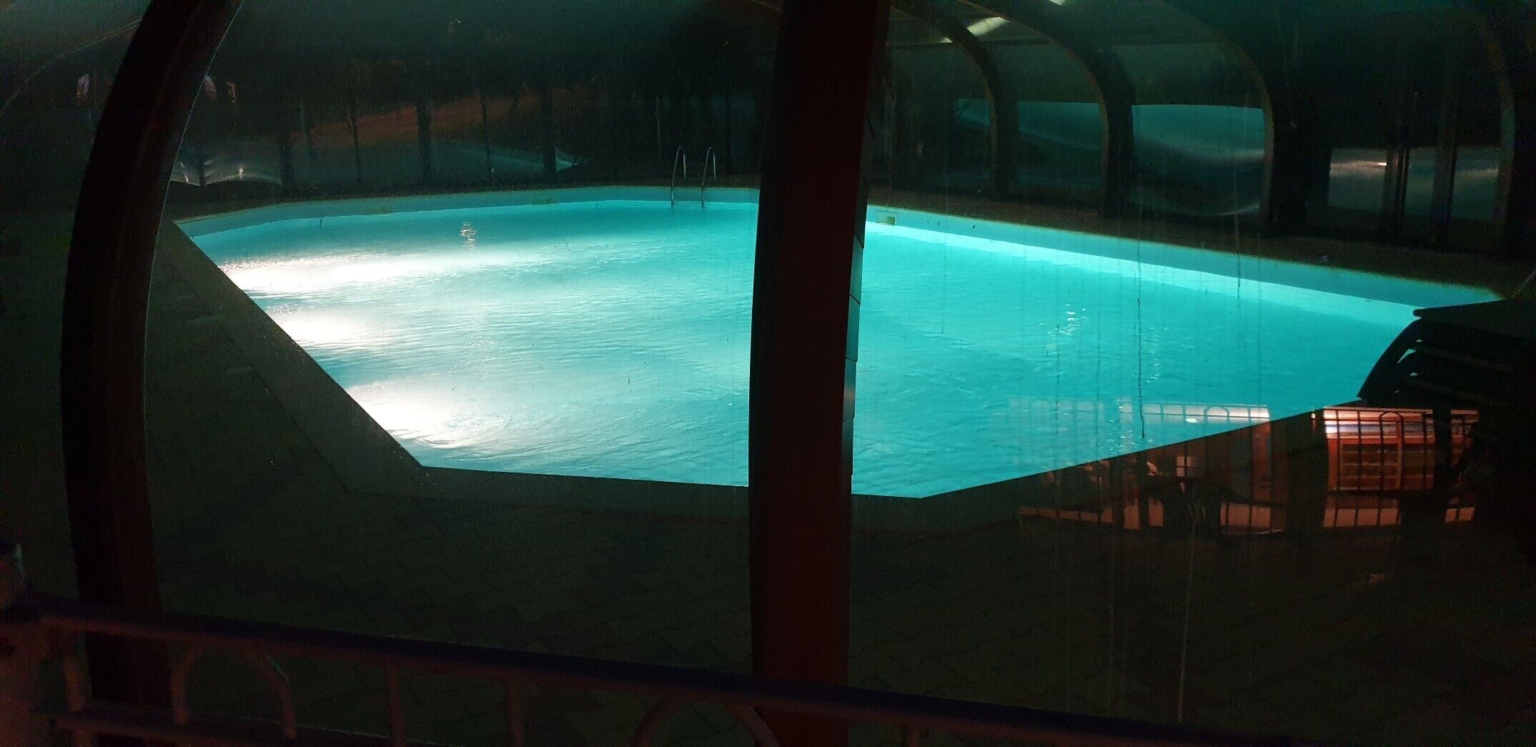 A swimming pool with a clear view of the water, surrounded by a glass enclosure.